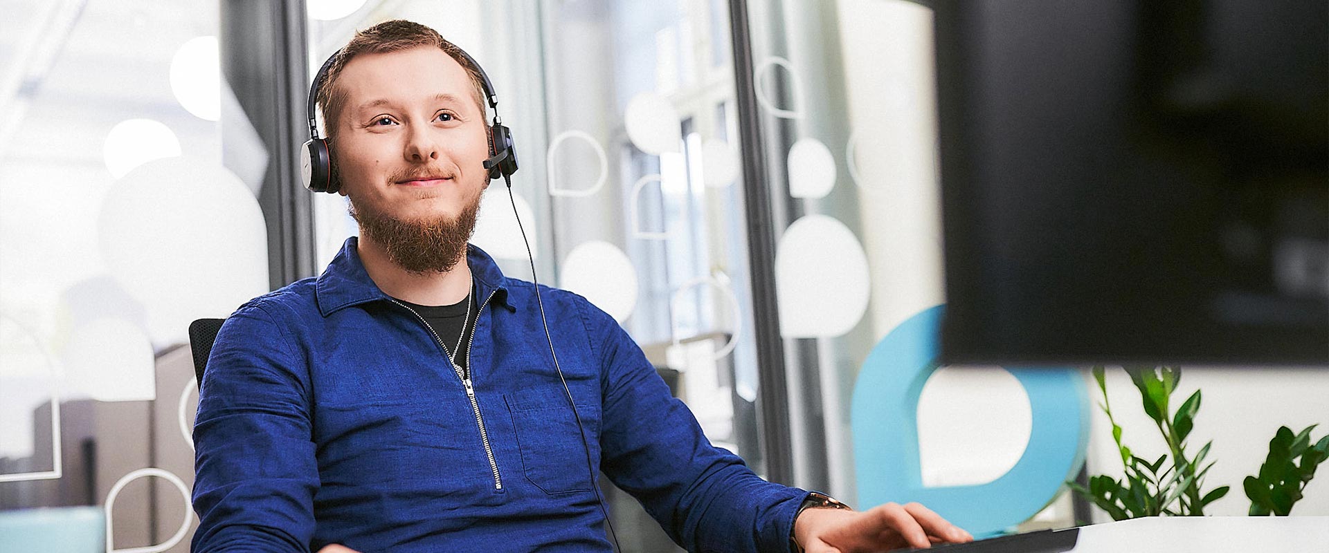 Kaiku24:n digihoitaja työskentelee tietokoneella kuulokemikrofoni päässään.